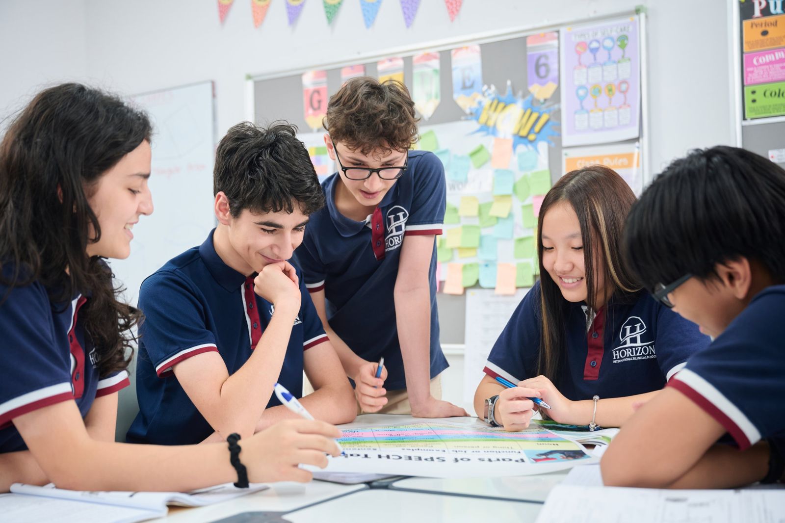 Five Horizon secondary students working together over a shared grammar chart