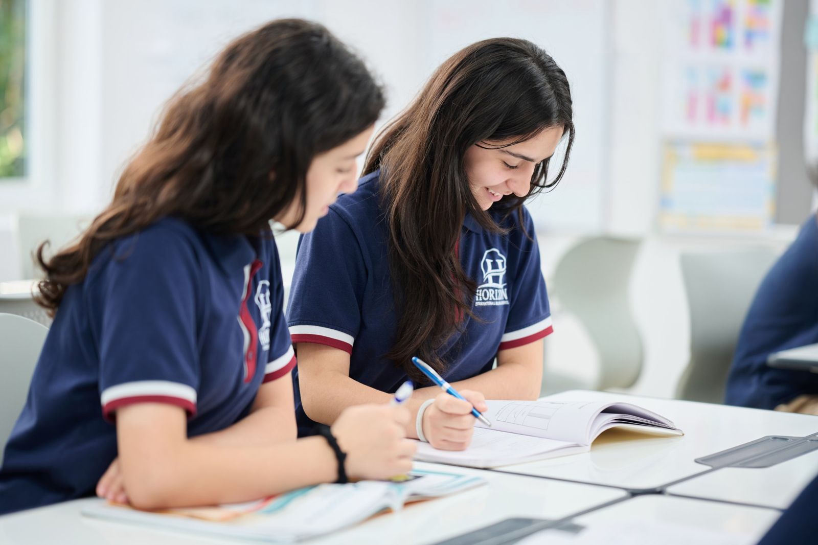 Two students writing in their workbooks